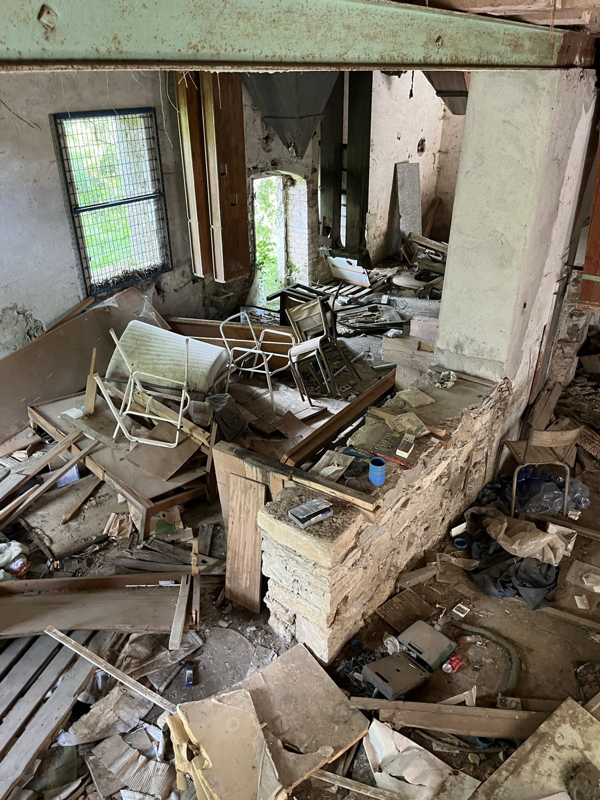 Grande salle remplie de meubles cassés et de gravats avant débarras