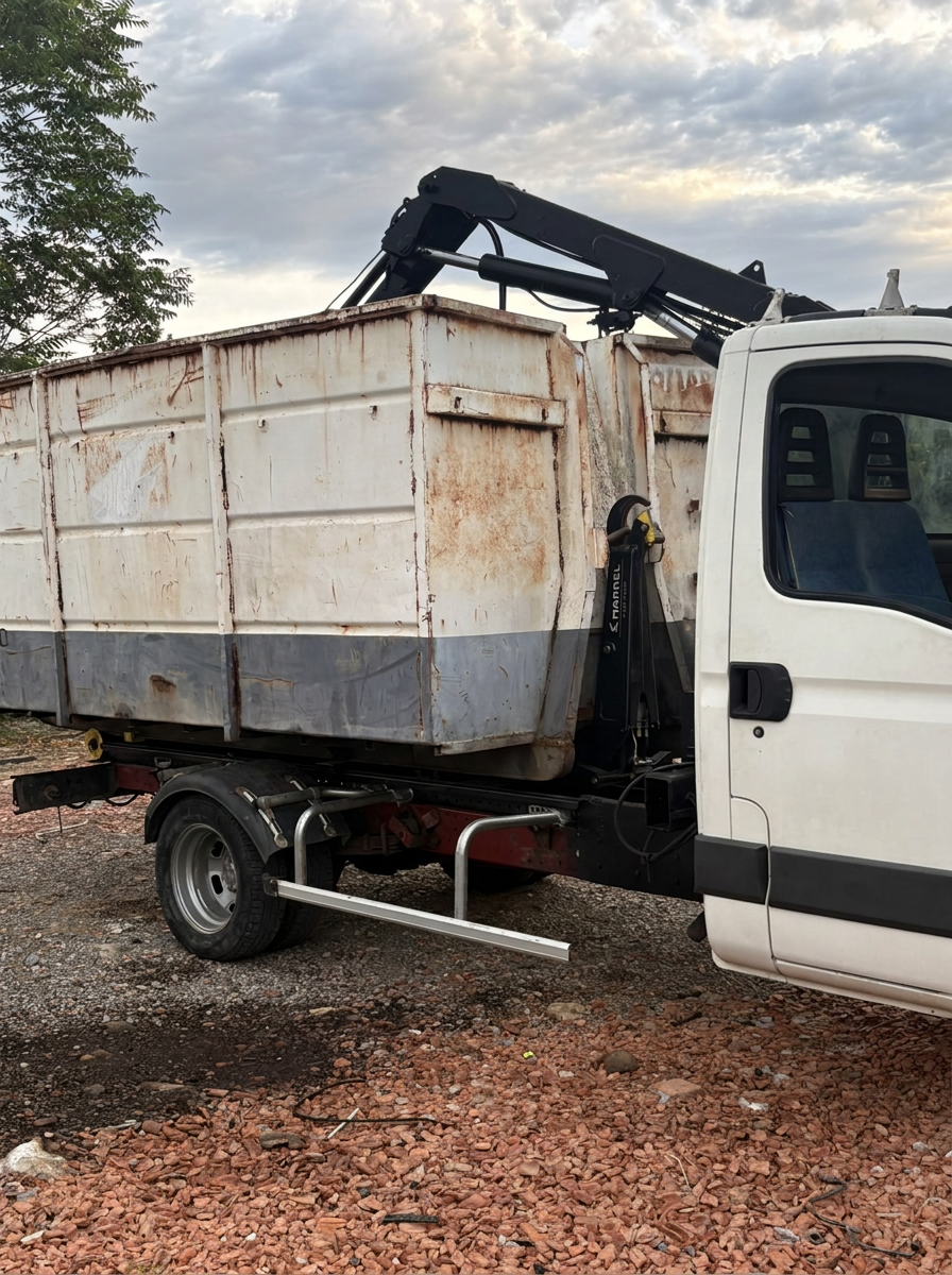 Camion ampliroll avec grue chargeant une benne